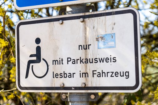 Behindertenparkplatz Ein Verkehrsschild an einem Behindertenparkplatz mit einem Rollstuhl-Symbol und dem Text "nur mit Parkausweis lesbar in Fahrzeug".