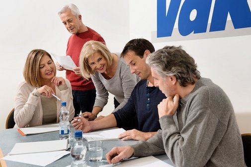 Besprechung im VdK-Büro Verschiedene Menschen sitzen an einem Tisch, offenbar in einer Arbeitssitzung, an der Wand hinter ihnen ist ein großes VdK-Logo.