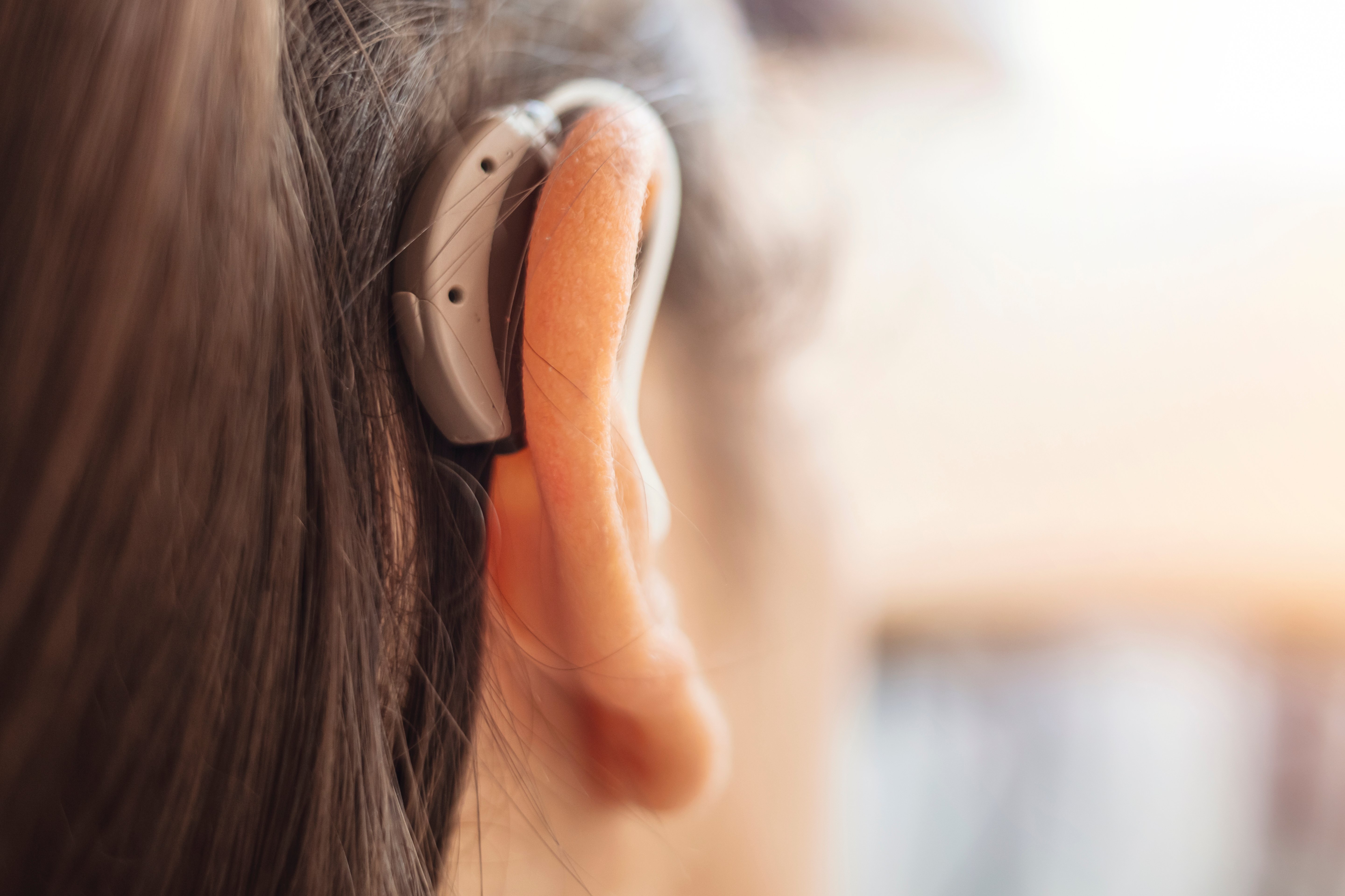 Kopf einer Frau mit einem H&ouml;rger&auml;t hinter dem rechten Ohr.