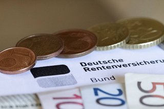 Münzen und Gelscheine liegen auf einem Bescheid der Deutschen Rentenversicherung.