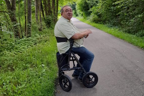 VdK-Mitglied Friedbert Johannes Friedbert Johannes auf einem Waldweg, er sitzt auf seinem Rollator.
