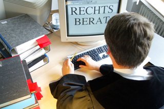 Symbolfoto: Ein Mann in Richterrobe am Computer. Auf dem Bildschirm steht das Wort "Rechtsberatung".