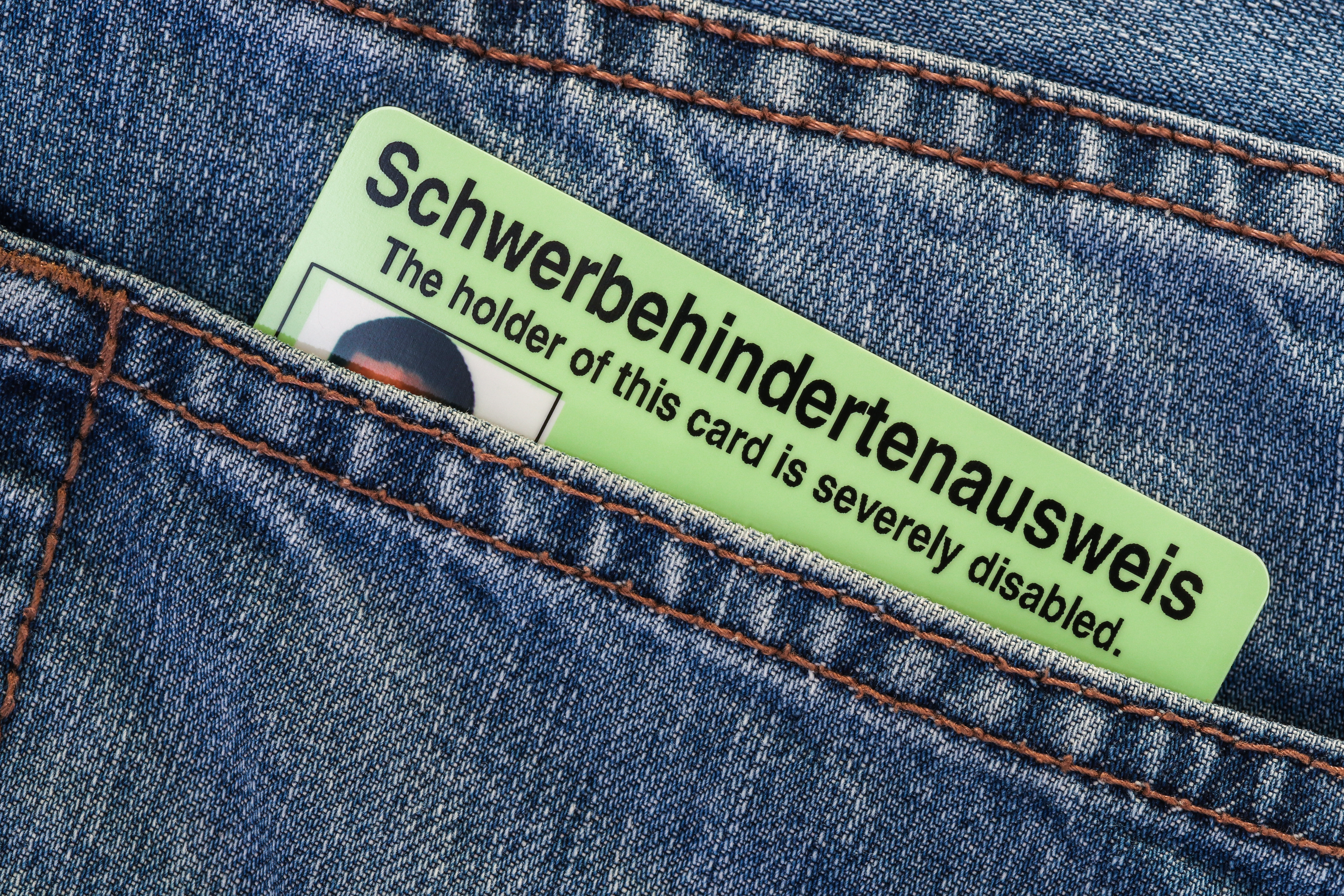 Schwerbehindertenausweis Eine hintere Jeanstasche, aus der ein Schwerbehindertenausweis im Scheckkartenformat herausschaut.