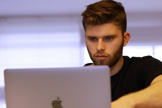 Junger Mann sitzt vor einem Computer.