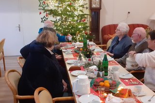 Personen am weihnachtlich gedeckten Tisch unterhalten sich angeregt