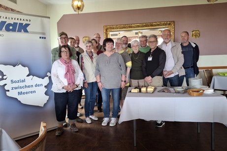 Mitglieder und Vorstand stehen neben dem Plakat des VdK Nord