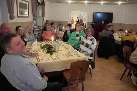 Fr&ouml;hlich winkende Teilnehmer am weihnachtlich dekoriertem Tisch.