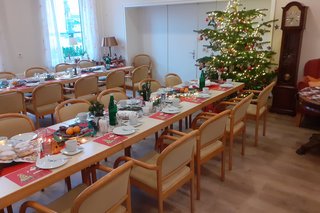 gedeckte Tische in weihnachtlichem Ambiente, im Hintergrund ein Weihnachtsbaum