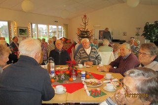 Personen sitzen an weihnachtlich gedecktem Tisch und unterhalten sich