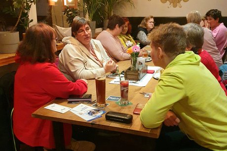 Die Frauen sitzen am Tisch.