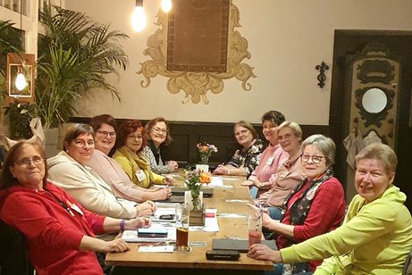 Die Frauen sitzen am Tisch.