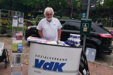 Der Bezirksverbandsvorsitzende Archibald Selinski steht hinter dem Infostand