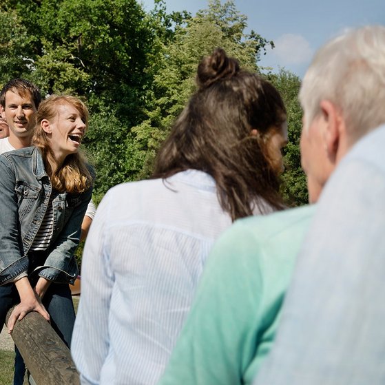 Gruppe von M&auml;nnern und Frauen unterschiedlichen Alters gemeinsam auf einer Wippe.