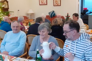 Personen bei einem gemütlichen Kaffeetrinken mit weihnachtlichem Gebäck