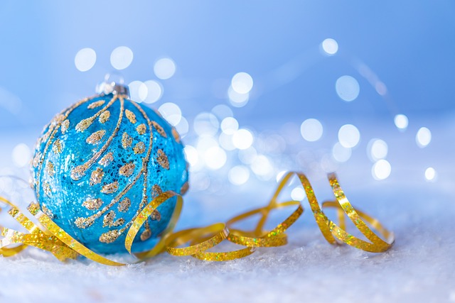 Eine blaue Weihnachtskugel mit goldenem Band im glitzernden Schnee.