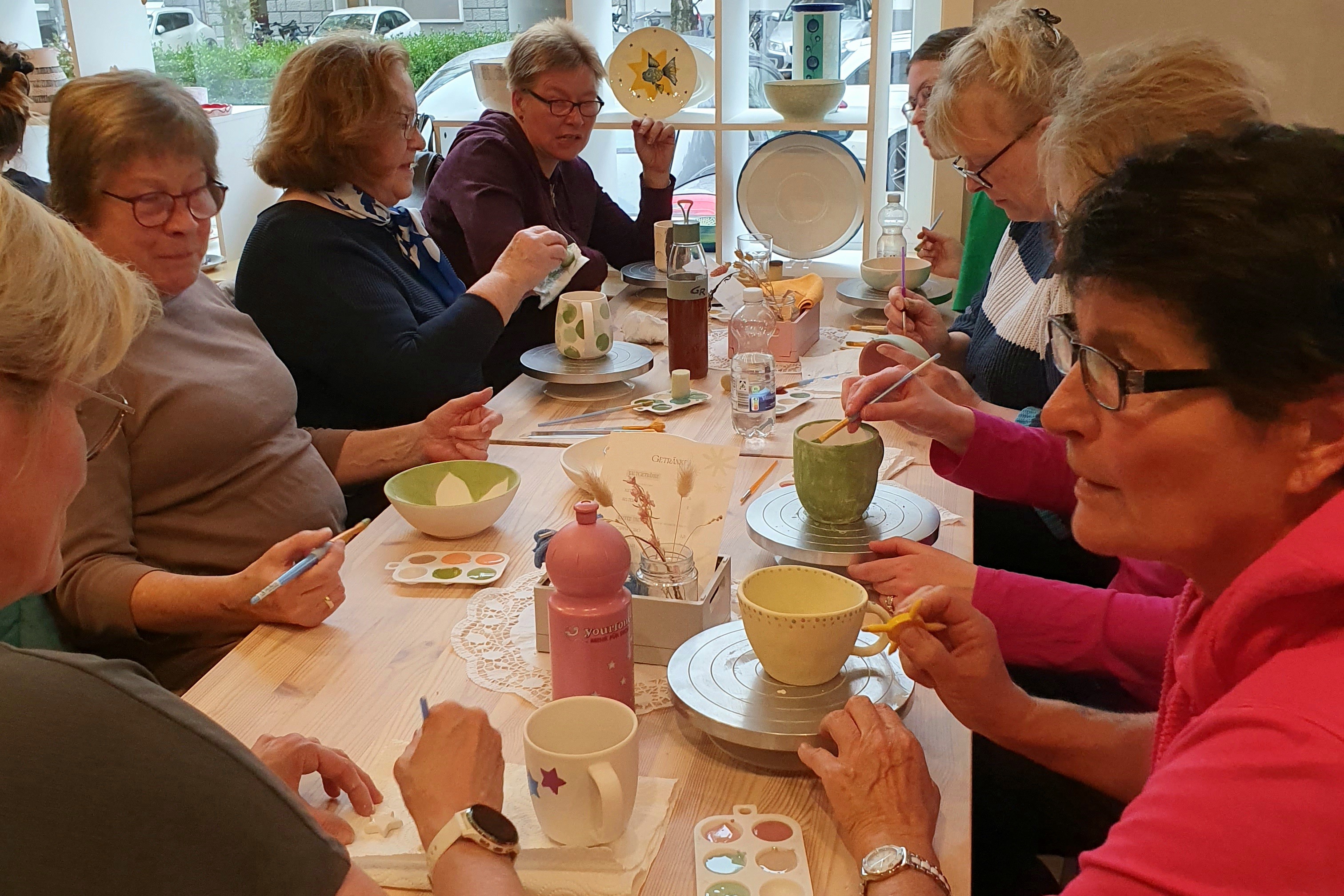 Es sind Fotos, die die Frauen beim Keramik bemalen zeigen.